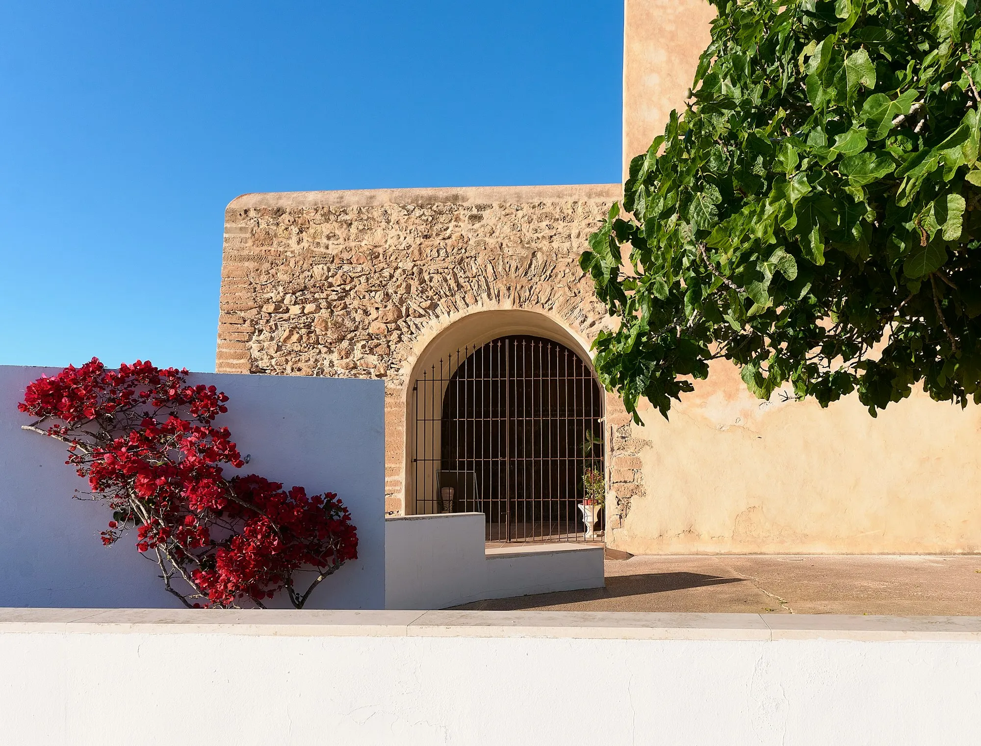 Stenen boogpoort met rode bougainvillea op Formentera